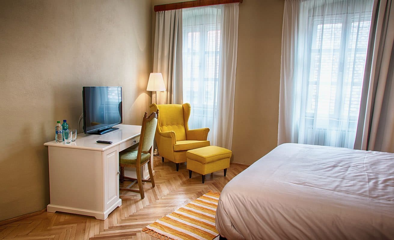 Cameră superioară, cu birou, televizor, fotoliu galben și fereastră dublă.